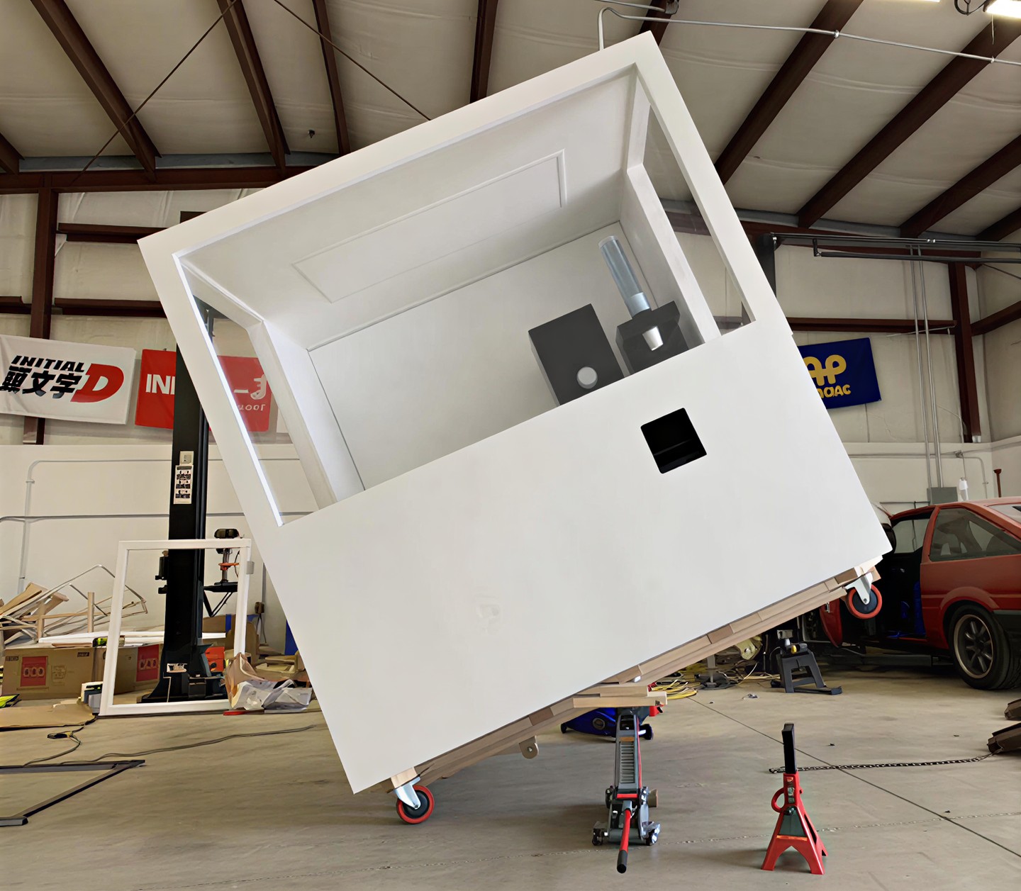 White machine cabin propped on jacks and casters on a shop floor, still being built