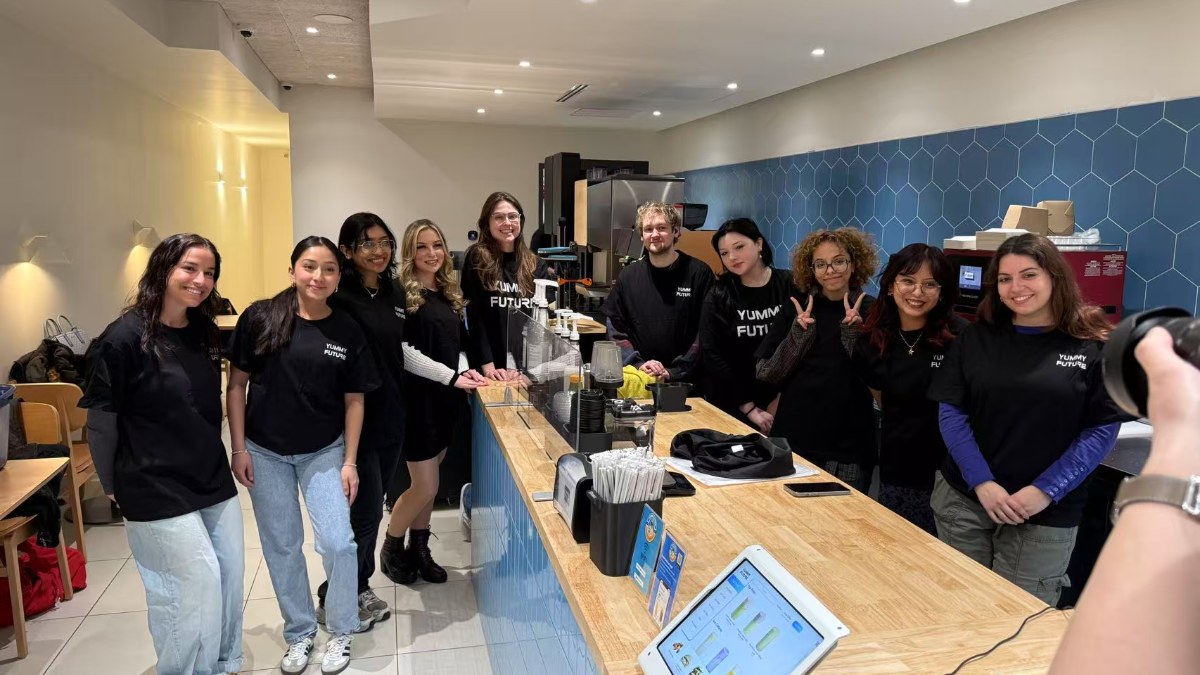 Eleven store crew members in black YUMMY FUTURE T-shirts standing behind the bar